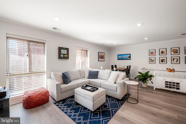 living room featuring crown molding, visible vents, and wood finished floors