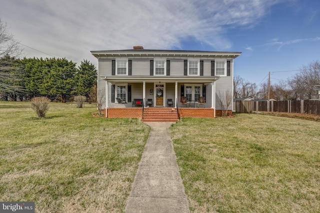 view of front facade with a porch, a chimney, a front yard, and fence