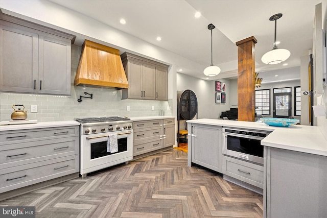 kitchen featuring decorative backsplash, custom range hood, high end range, light countertops, and gray cabinetry