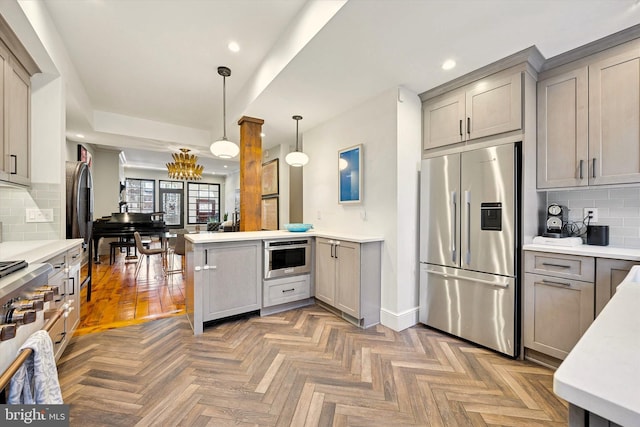 kitchen featuring a peninsula, appliances with stainless steel finishes, light countertops, and gray cabinetry