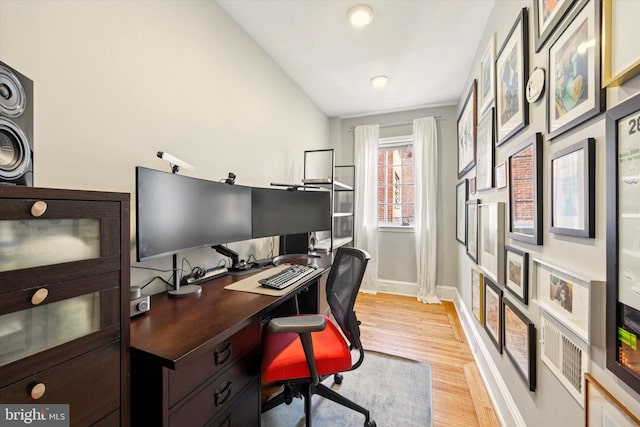 office space with light wood-type flooring, vaulted ceiling, and baseboards