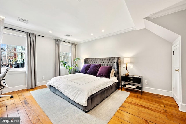 bedroom featuring crown molding, hardwood / wood-style flooring, visible vents, and baseboards