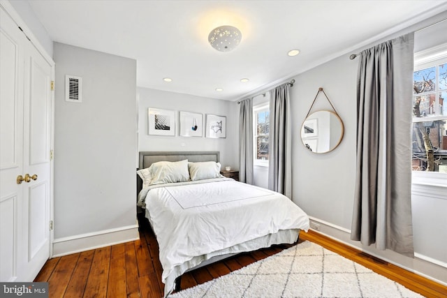 bedroom featuring wood-type flooring, multiple windows, visible vents, and baseboards