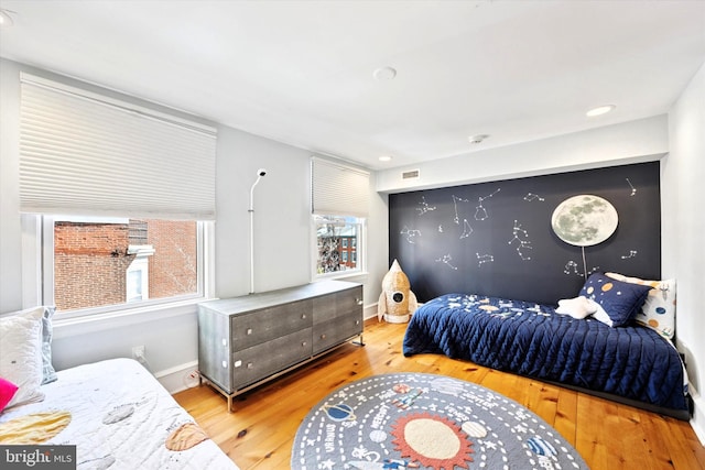 bedroom with wood finished floors, visible vents, and baseboards