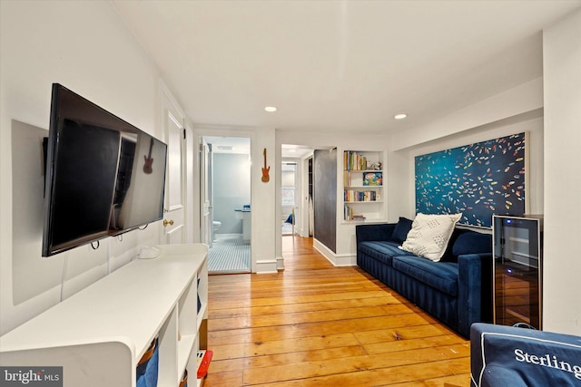 living room with light wood finished floors, built in shelves, baseboards, and recessed lighting