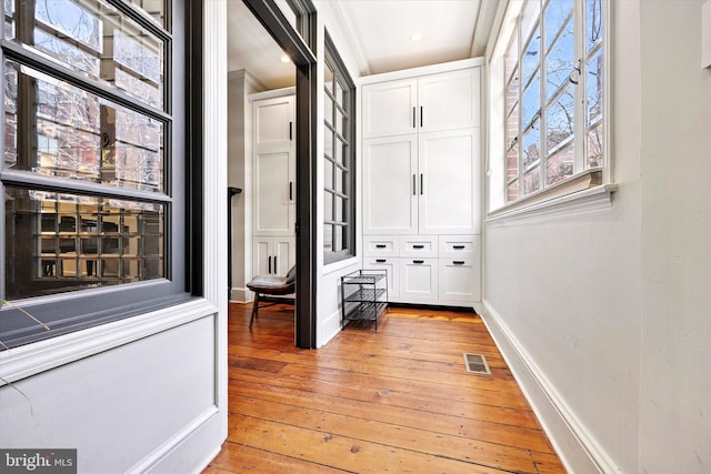 corridor featuring light wood finished floors, baseboards, and visible vents