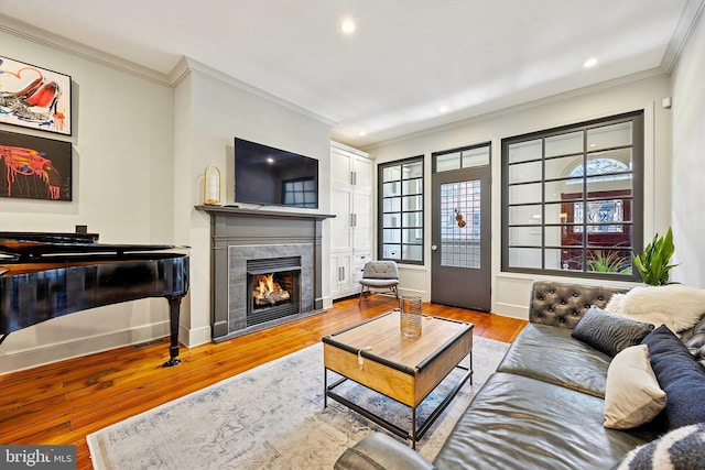 living area with baseboards, wood finished floors, a tile fireplace, and crown molding