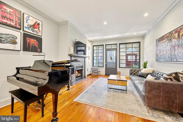 sitting room featuring ornamental molding, a tile fireplace, hardwood / wood-style flooring, and baseboards