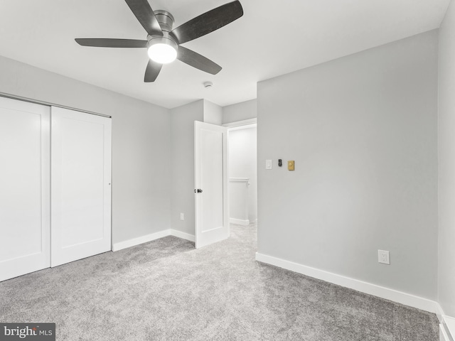 unfurnished bedroom with carpet floors, ceiling fan, baseboards, and a closet