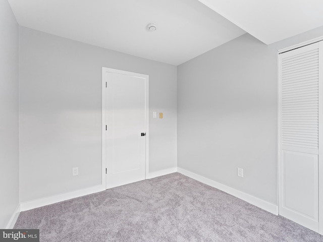 unfurnished bedroom with a closet, carpet flooring, and baseboards