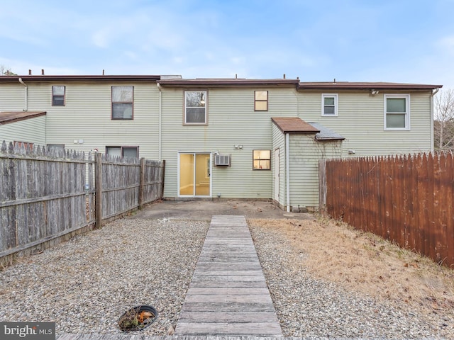 rear view of house with a patio area, a fenced backyard, and a wall unit AC