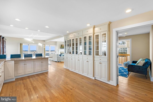 kitchen with recessed lighting, light wood-type flooring, and glass insert cabinets