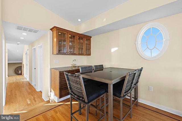 dining space with indoor wet bar, light wood-style flooring, recessed lighting, and visible vents