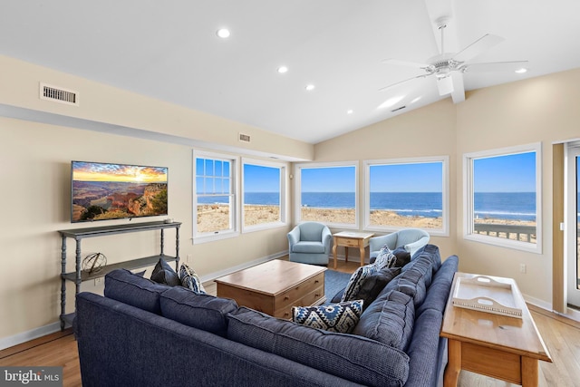 living area with light wood finished floors, visible vents, baseboards, a water view, and vaulted ceiling