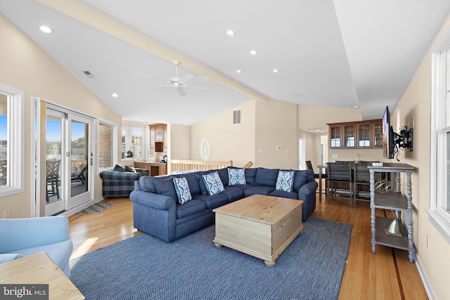 living area featuring vaulted ceiling with beams, wood finished floors, and visible vents