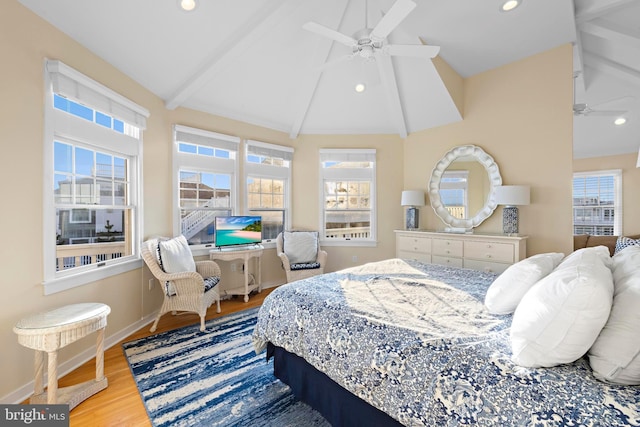 bedroom with beamed ceiling, multiple windows, baseboards, and wood finished floors