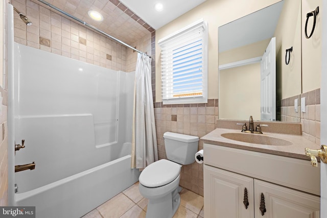 bathroom with tile patterned flooring, tile walls, toilet, shower / bath combo with shower curtain, and vanity