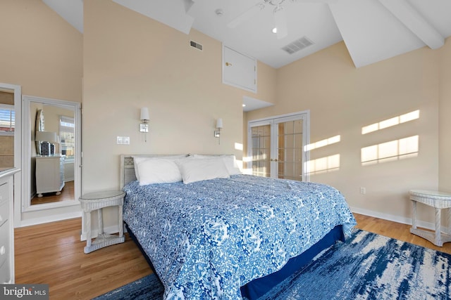 bedroom featuring french doors, high vaulted ceiling, visible vents, and wood finished floors