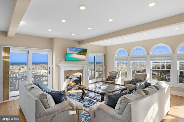 living room with recessed lighting, beam ceiling, a high end fireplace, and light wood finished floors