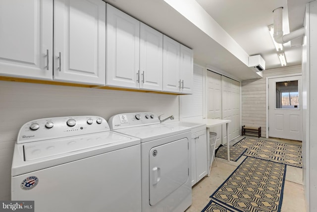 clothes washing area featuring cabinet space, separate washer and dryer, wood walls, and light tile patterned flooring