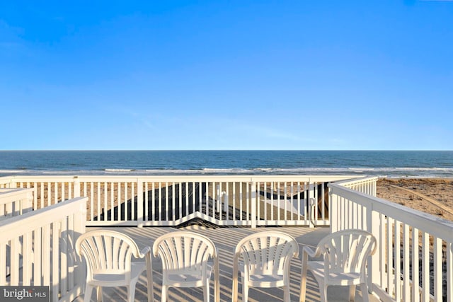 wooden terrace featuring a view of the beach and a water view