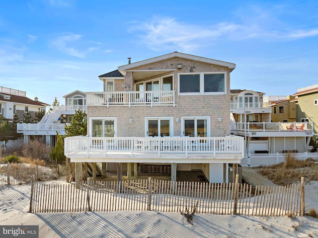 rear view of house with a balcony, fence private yard, and stairs