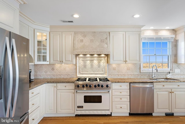 kitchen with visible vents, light wood-type flooring, a sink, appliances with stainless steel finishes, and custom exhaust hood