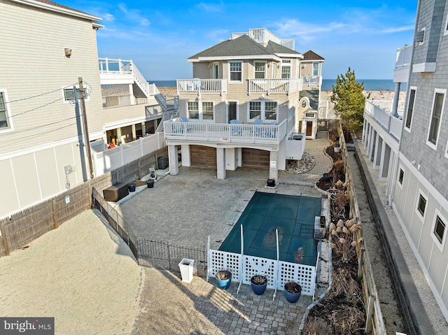 rear view of property with a water view, a swimming pool, a fenced backyard, a garage, and a patio area