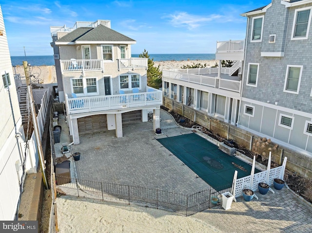 rear view of house with an attached garage, fence, and a water view