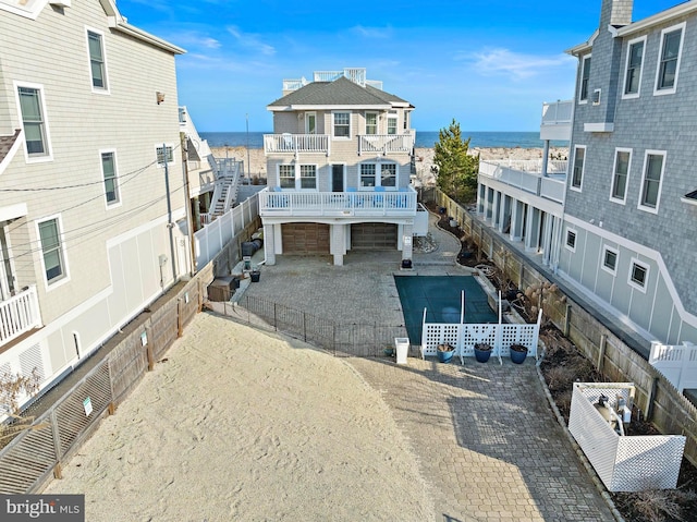 rear view of property featuring aphalt driveway, a fenced backyard, an attached garage, and a balcony