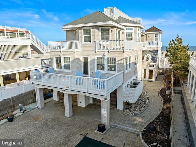 rear view of property with a patio, roof with shingles, and fence