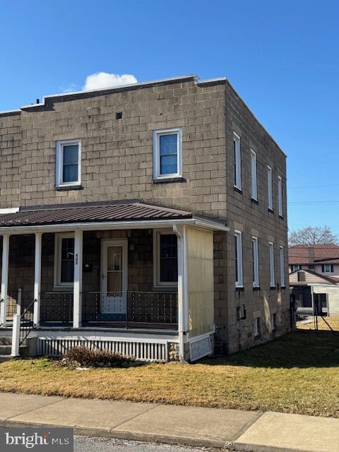 multi unit property featuring a porch, a front yard, and a shingled roof