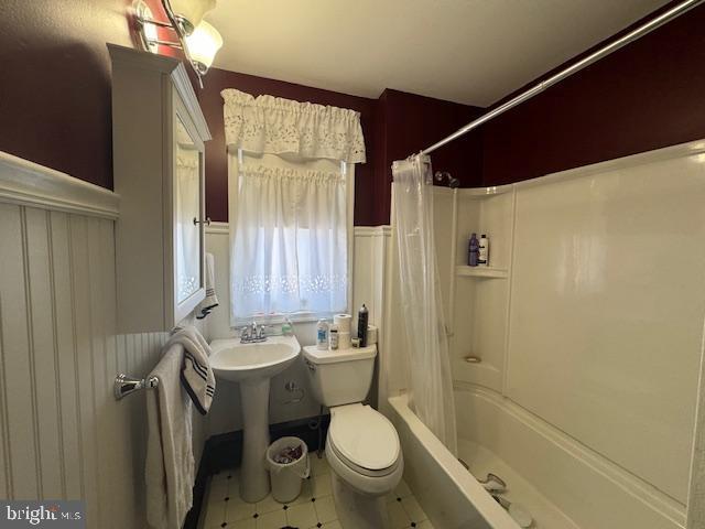 full bathroom featuring a sink, wainscoting, shower / bath combo with shower curtain, and toilet