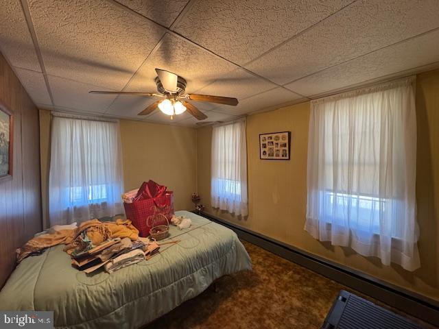 bedroom with a paneled ceiling, ceiling fan, and carpet