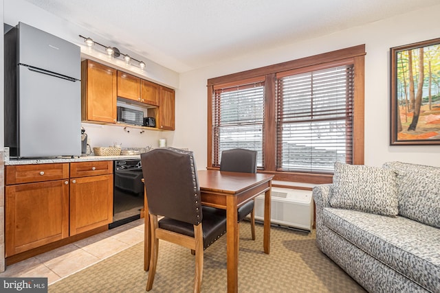 kitchen with brown cabinetry, black dishwasher, a textured ceiling, and light tile patterned floors