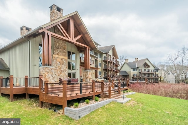 rear view of property with a deck, a lawn, and a chimney