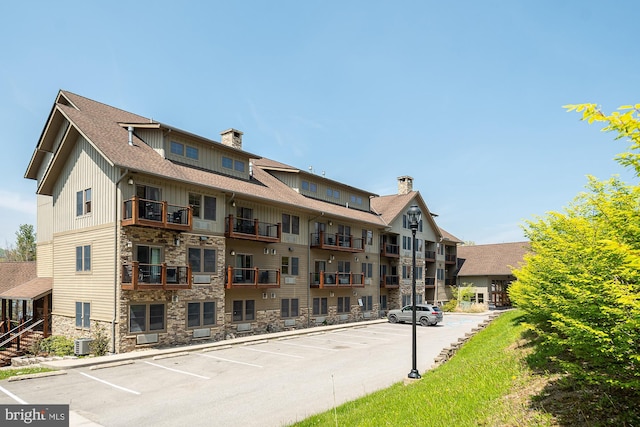 view of building exterior featuring uncovered parking and central AC