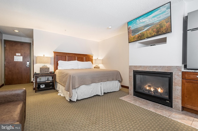 bedroom featuring a textured ceiling, a tile fireplace, and light colored carpet