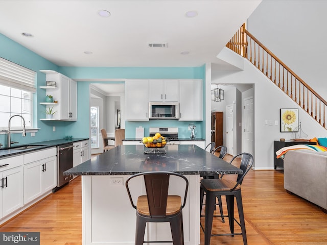 kitchen with white cabinets, a sink, appliances with stainless steel finishes, and a breakfast bar