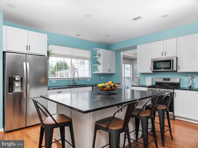 kitchen featuring white cabinets, a sink, light wood-style floors, and appliances with stainless steel finishes