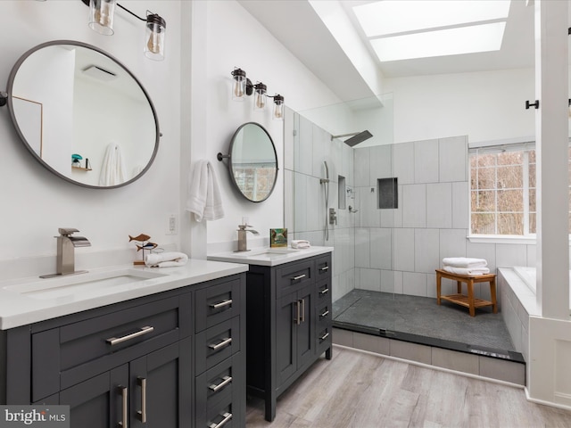 full bathroom featuring a sink, a walk in shower, a skylight, and wood finished floors