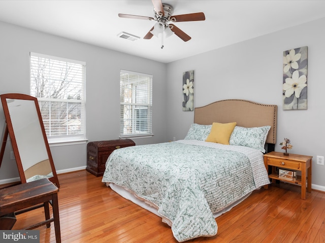 bedroom featuring baseboards, visible vents, hardwood / wood-style flooring, and a ceiling fan