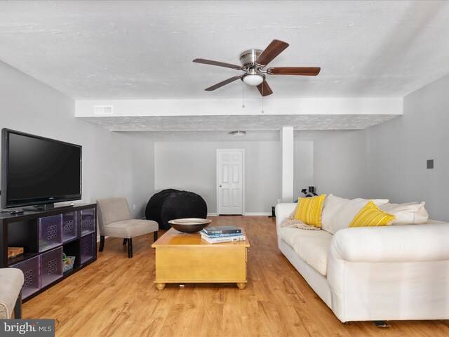 living area with a textured ceiling, ceiling fan, visible vents, and wood finished floors