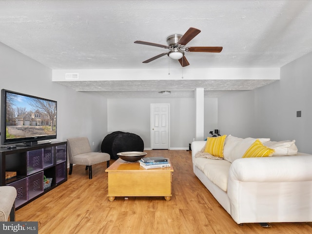 living room with a textured ceiling, ceiling fan, visible vents, and wood finished floors