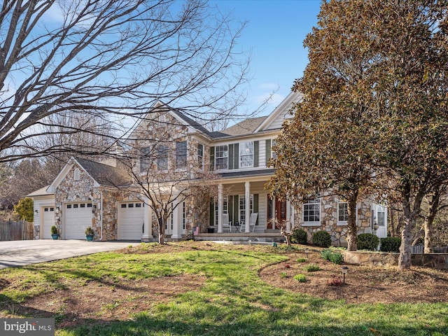 view of front of home featuring stone siding, concrete driveway, an attached garage, fence, and a porch