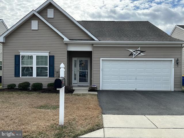 ranch-style house featuring driveway, a front lawn, roof with shingles, and an attached garage