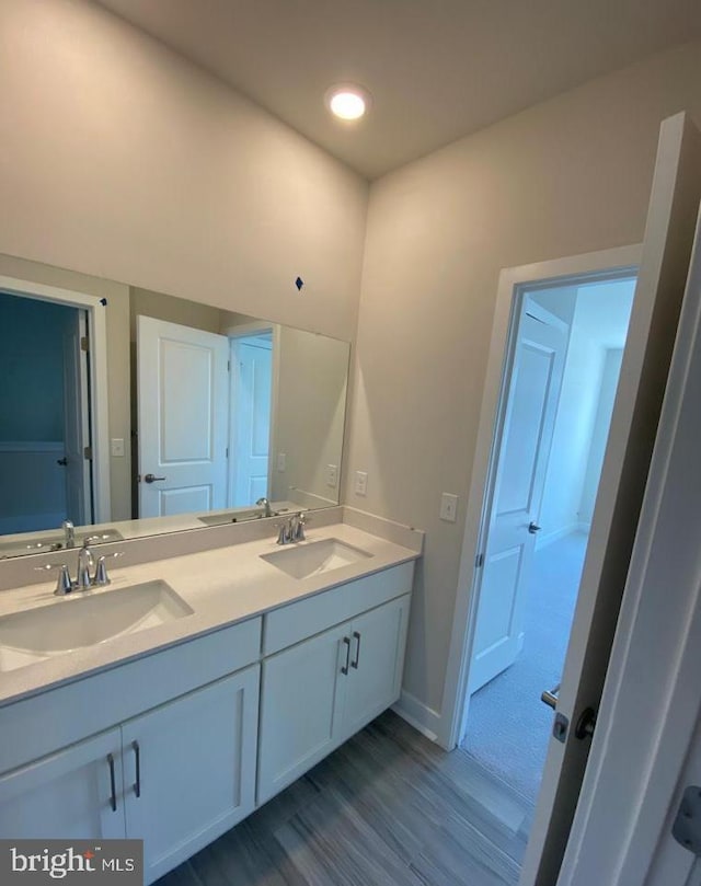 bathroom with double vanity, wood finished floors, and a sink