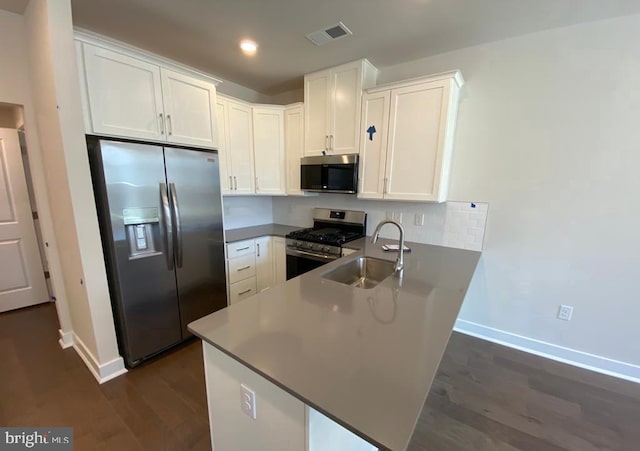 kitchen with visible vents, appliances with stainless steel finishes, white cabinets, a sink, and a peninsula