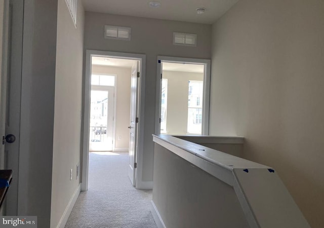 corridor featuring baseboards, light carpet, visible vents, and an upstairs landing