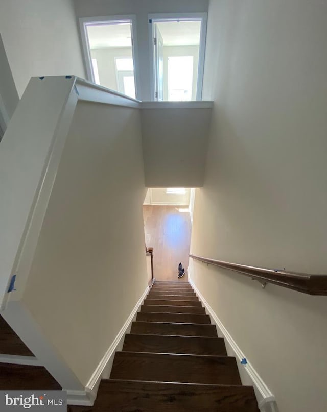 staircase with baseboards and wood finished floors